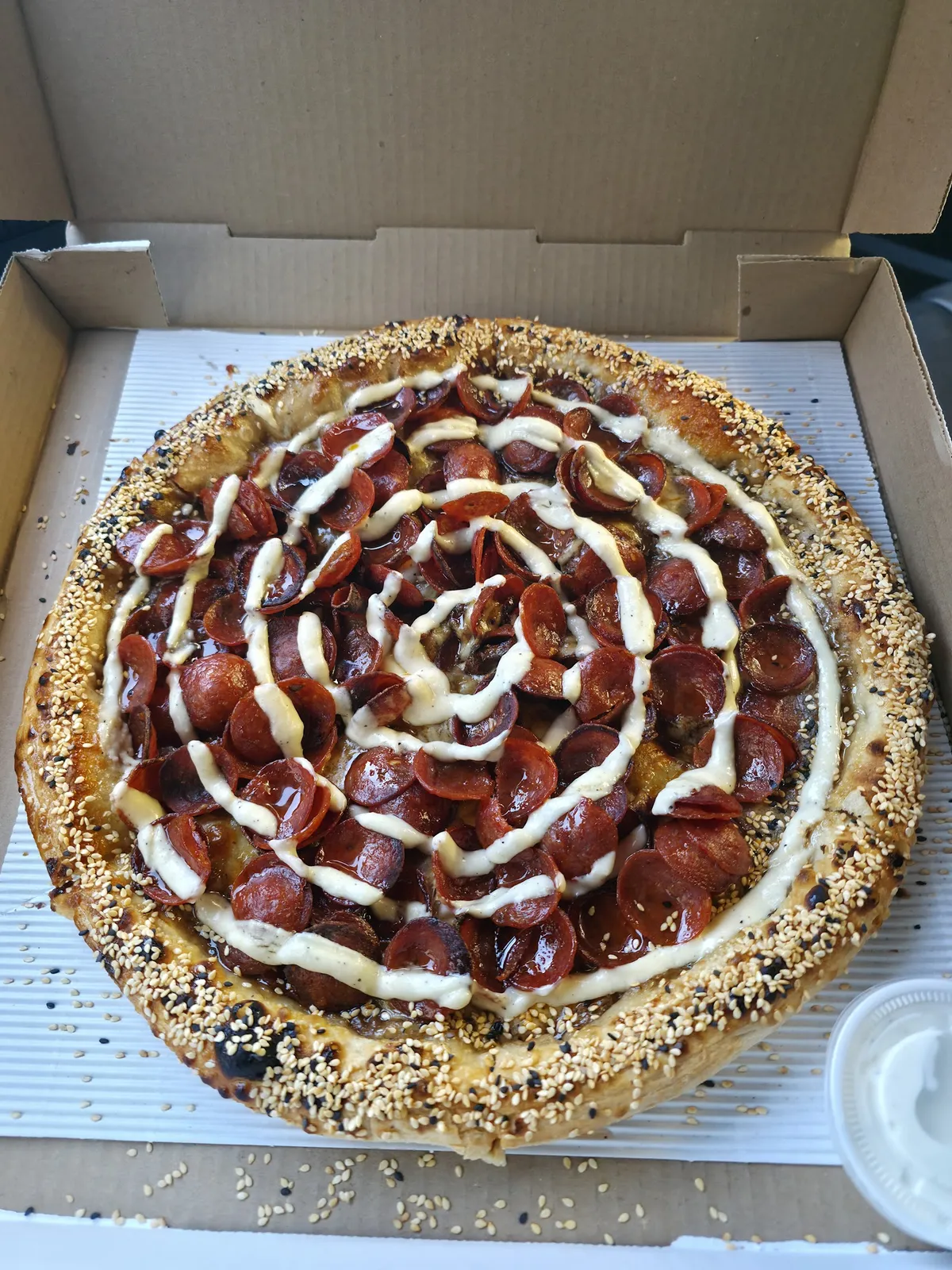 Pepperoni pizza with sesame seed crust in a box