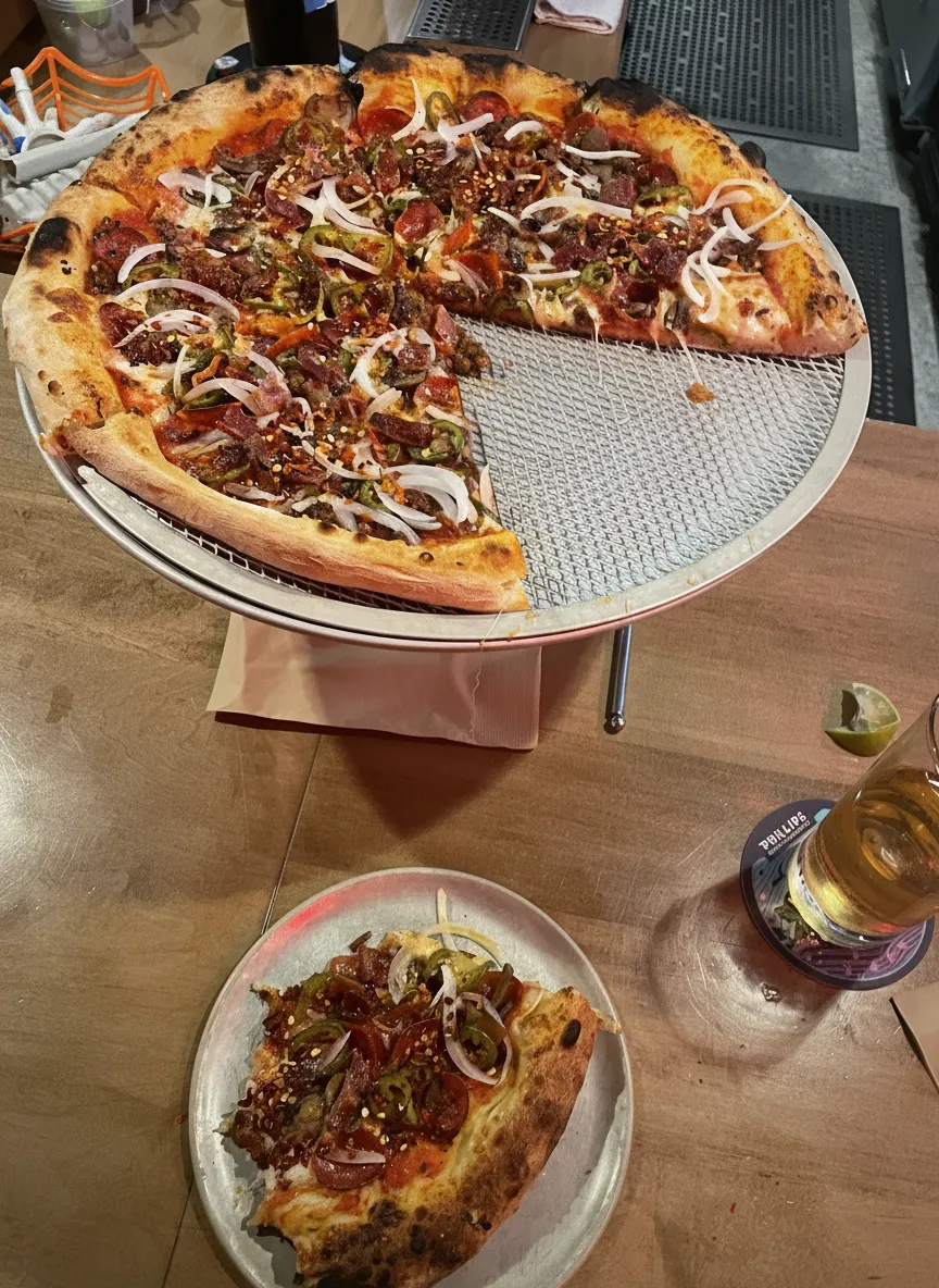 Large pizza with a slice on a plate and a beer